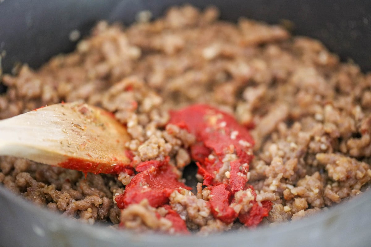 Cooking meat and tomato paste in a pot for lasagna soup
