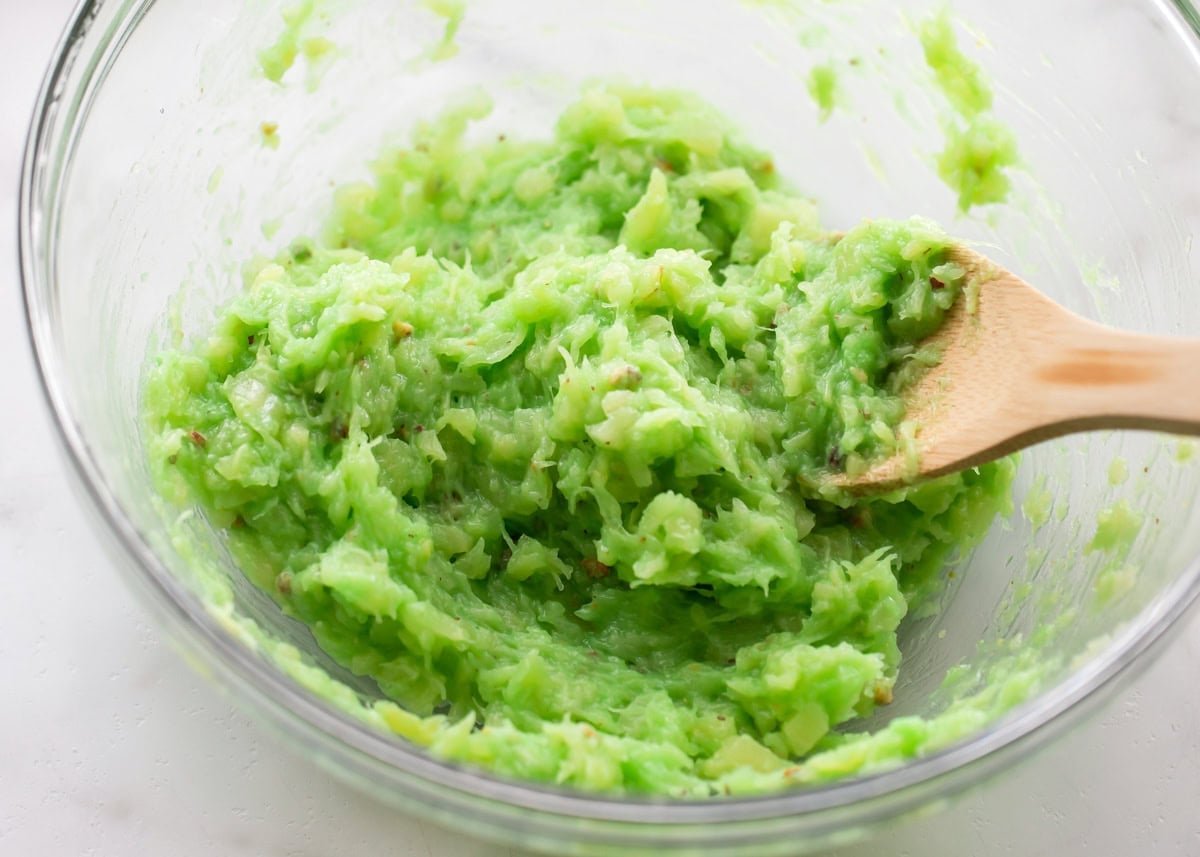 Crushed pineapple and instant pistachio pudding mix in glass bowl.
