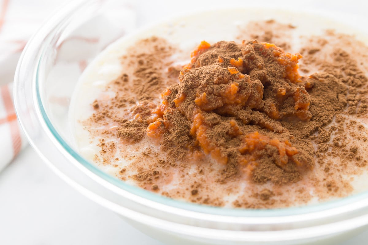 pumpkin puree, cinnamon, and milk in a glass mixing bowl