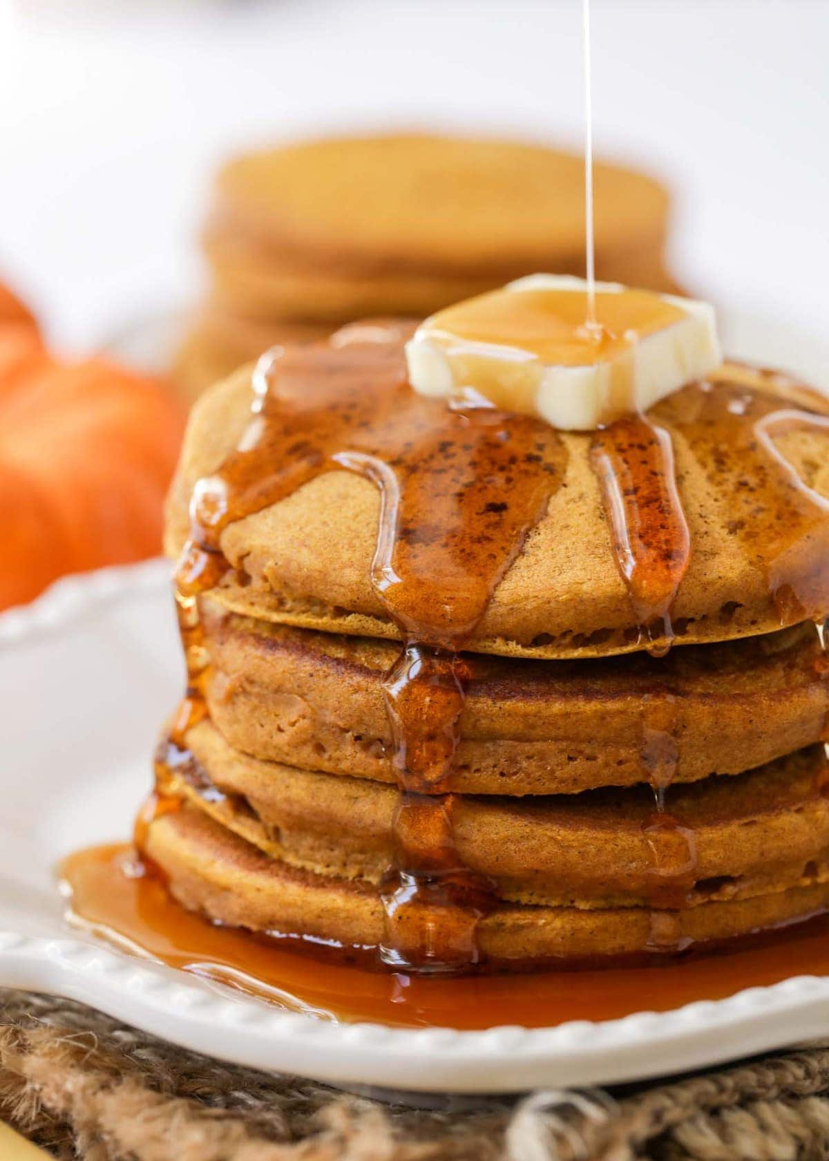 Easy pancake recipe - Pumpkin pancakes stacked with syrup on them.