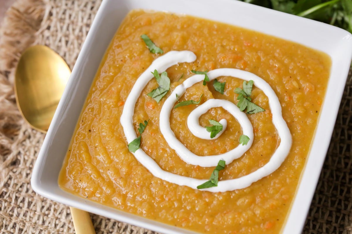 Fall soup recipes - butternut squash soup topped with cream and fresh herbs.