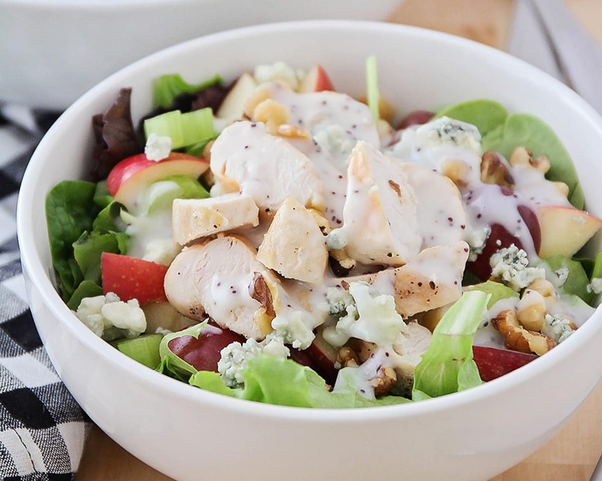 Waldorf salad topped with dressing in a white bowl.