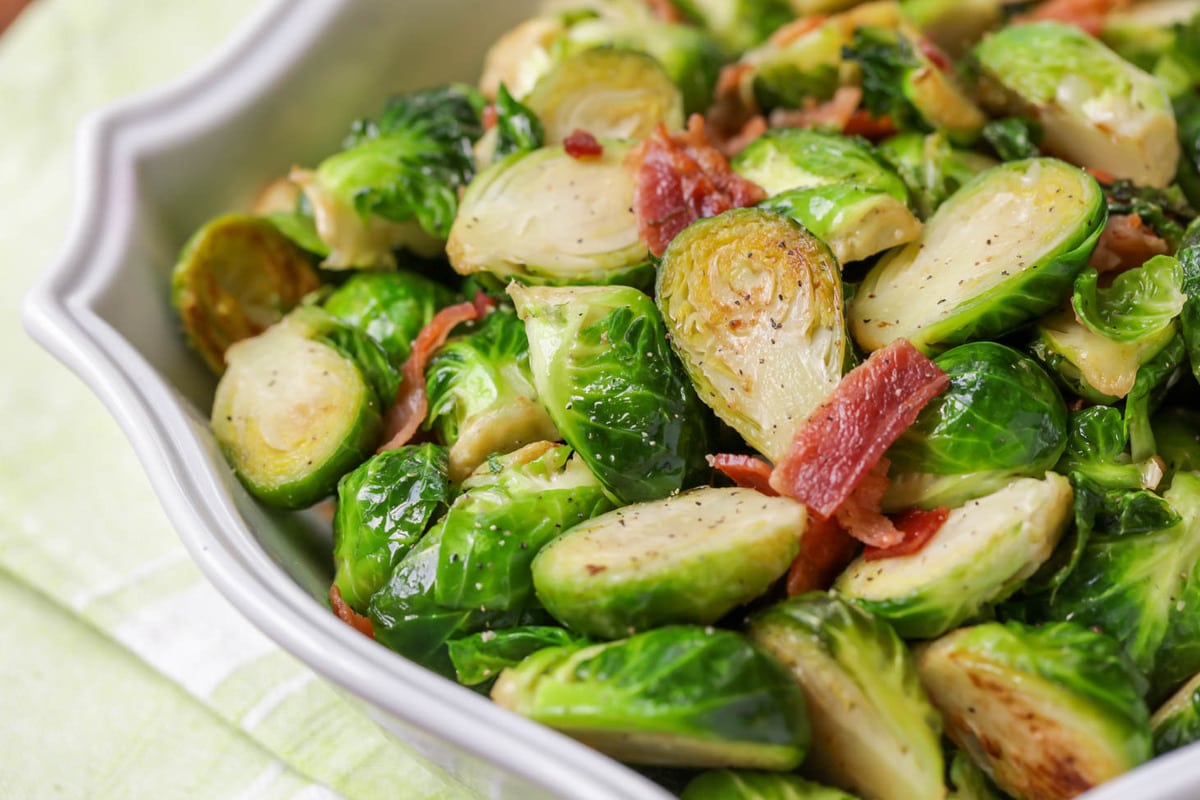 Bacon and brussel sprouts served in a white bowl.