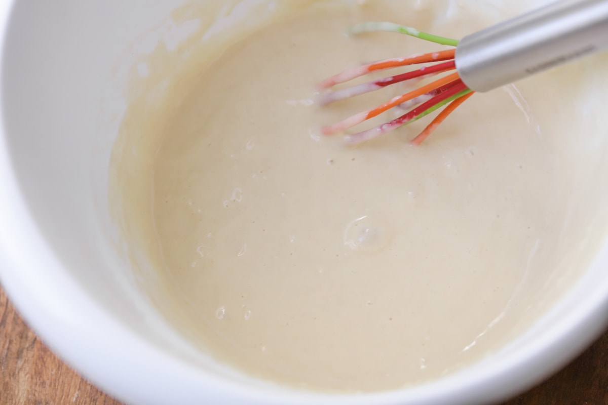 Funnel Cake Batter in bowl with a whisk.