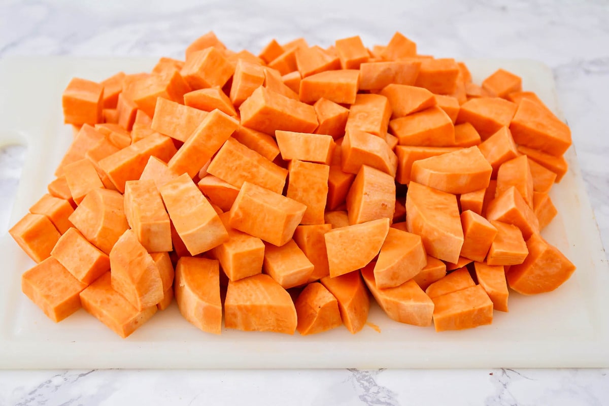 Cubes of uncooked sweet potatoes on cutting board