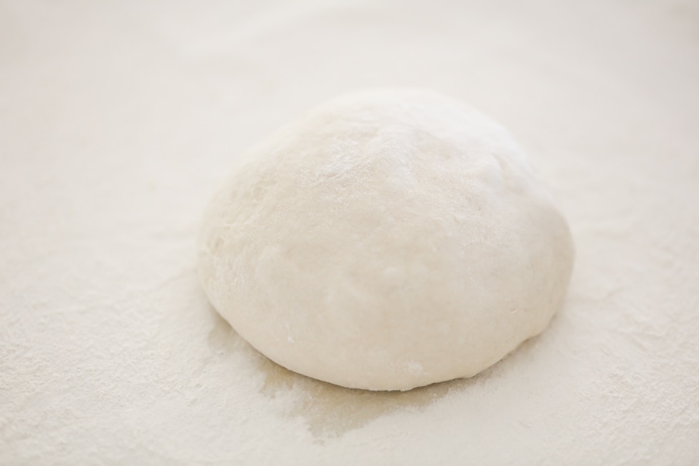 Pizza dough on a floured work surface.