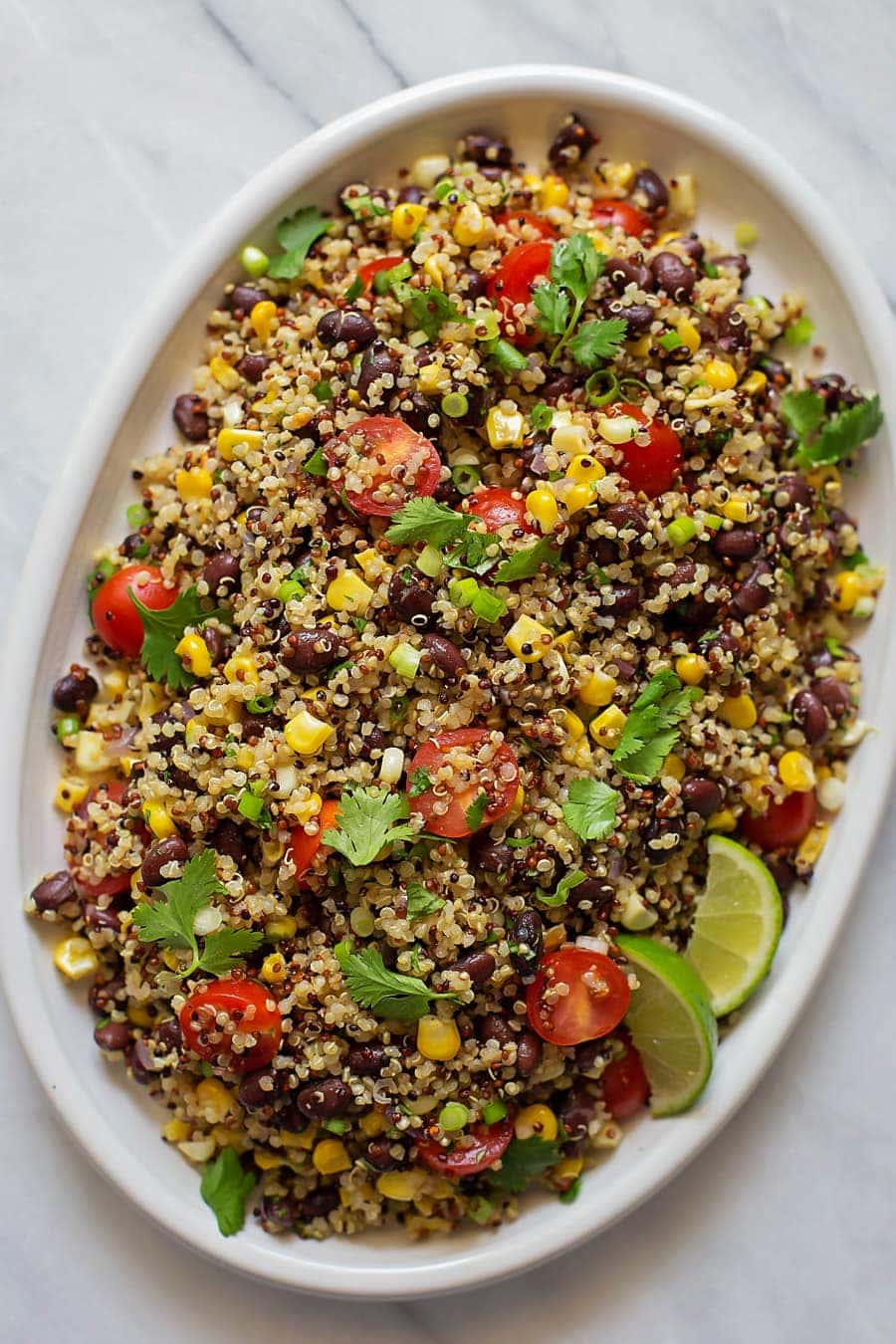Quinoa Black Bean Salad topped with fresh cilantro and limes served in a white platter