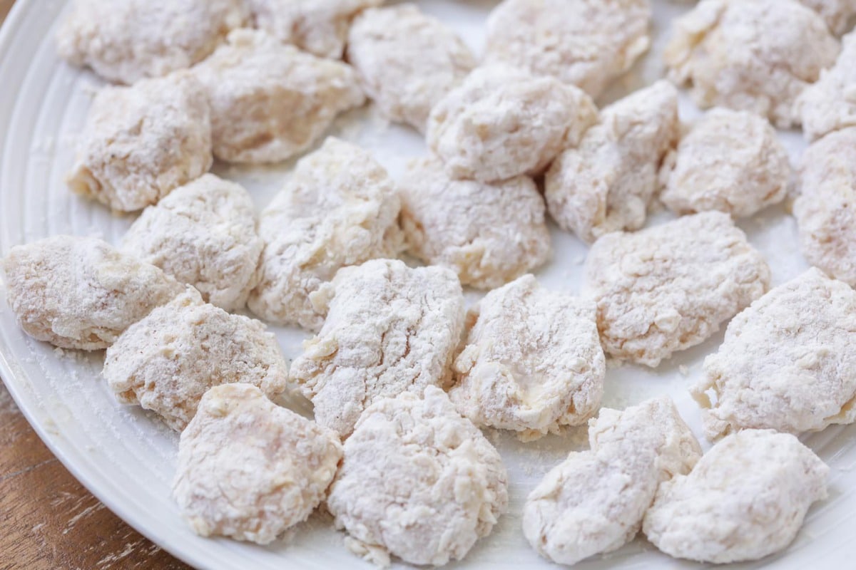 Homemade honey bbq boneless wings dredged in flour on a plate.