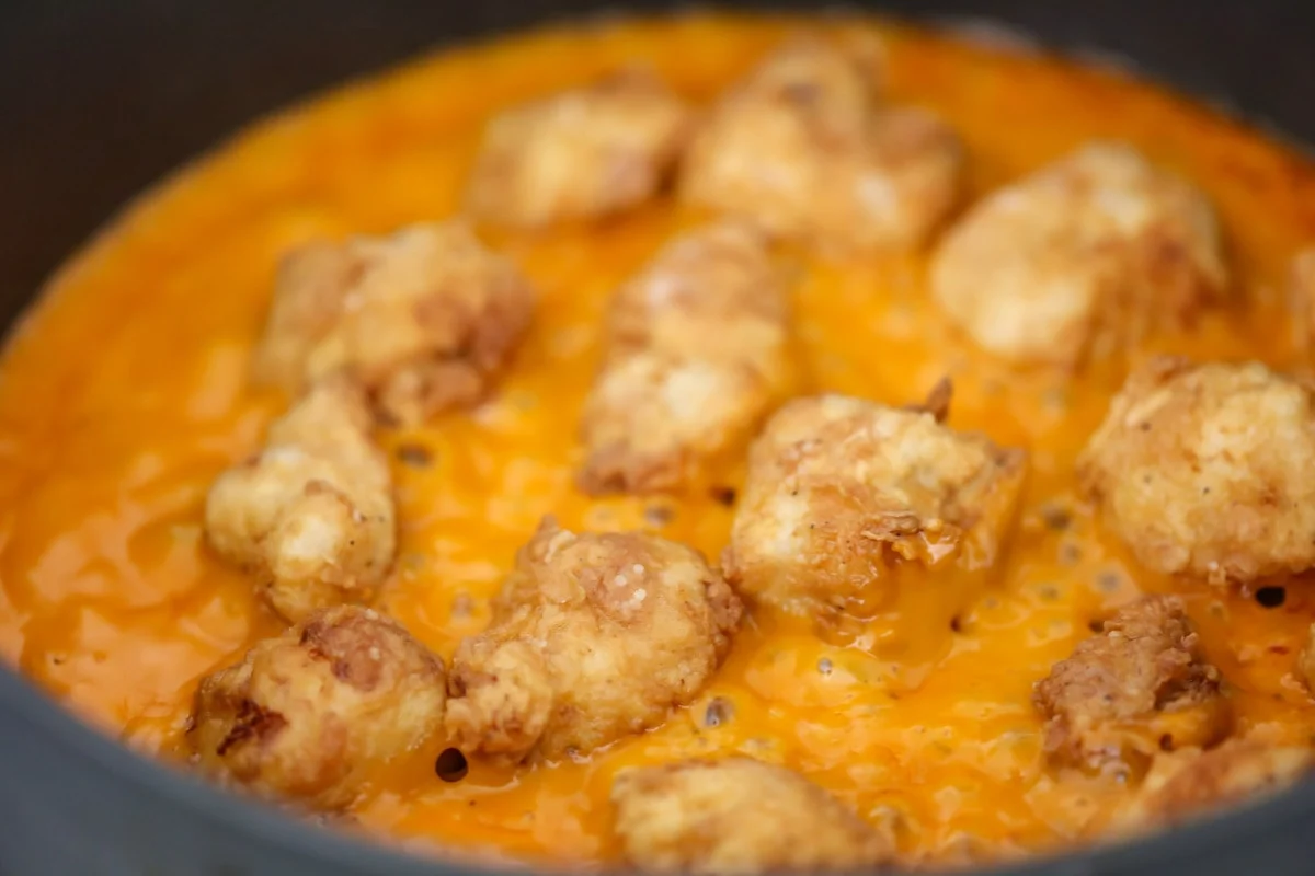 Boneless Buffalo Wings simmering in a buffalo sauce.