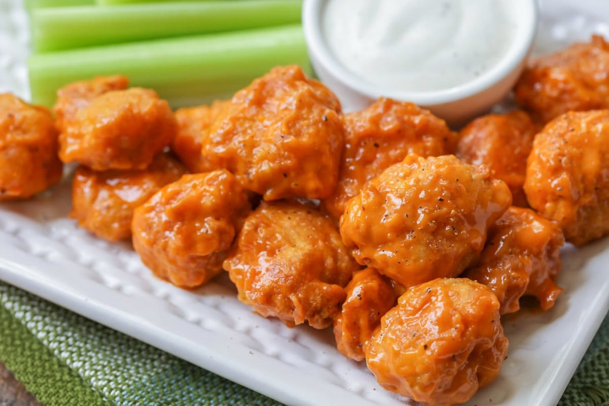 4th of July Appetizers - Boneless buffalo wings on a white platter with celery sticks and ranch.