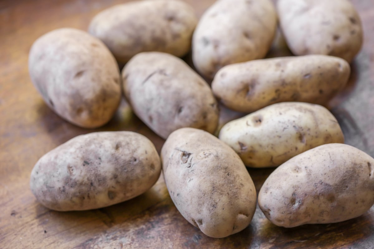 Russet potatoes piled on a kitchen table.