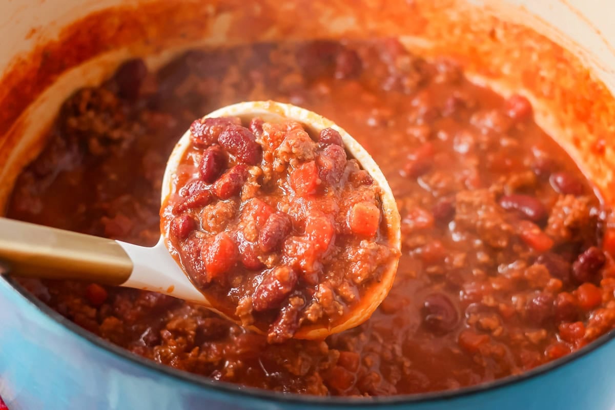 Chili recipe being scooped out of pot.