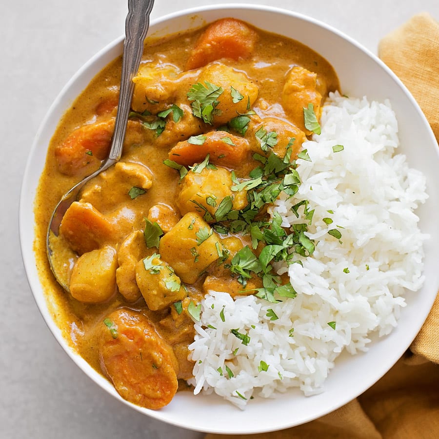 Sunday Dinner Ideas - White bowl of coconut curry chicken served with white rice.