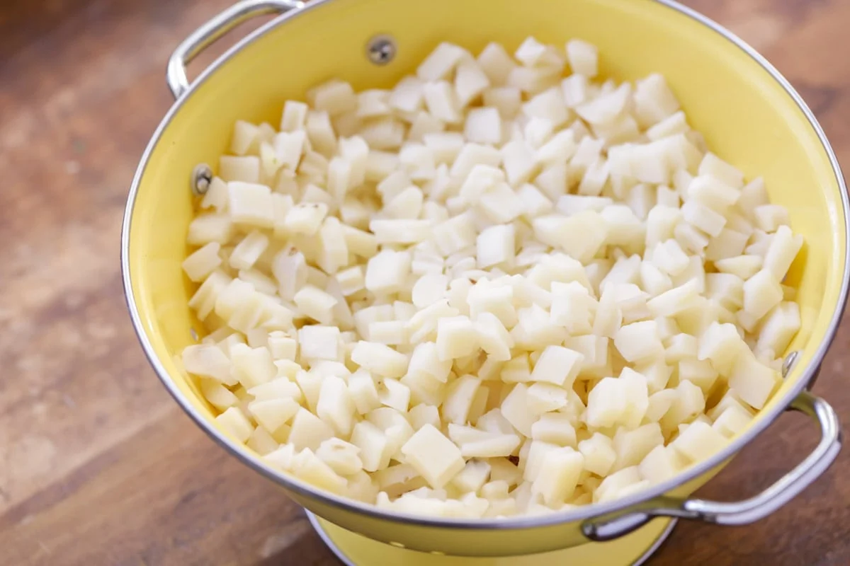 Hash browns drained in a yellow colander.