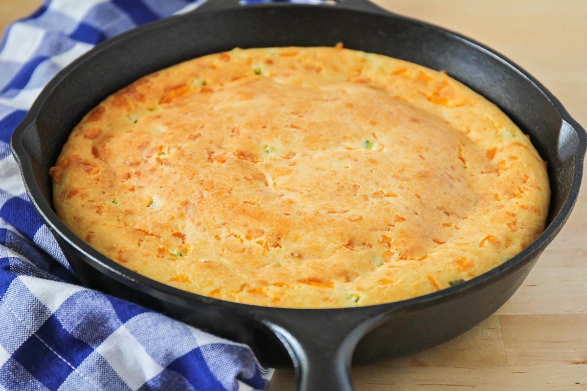 Mexican Cornbread recipe filled with diced jalapenos in a cast iron skillet.