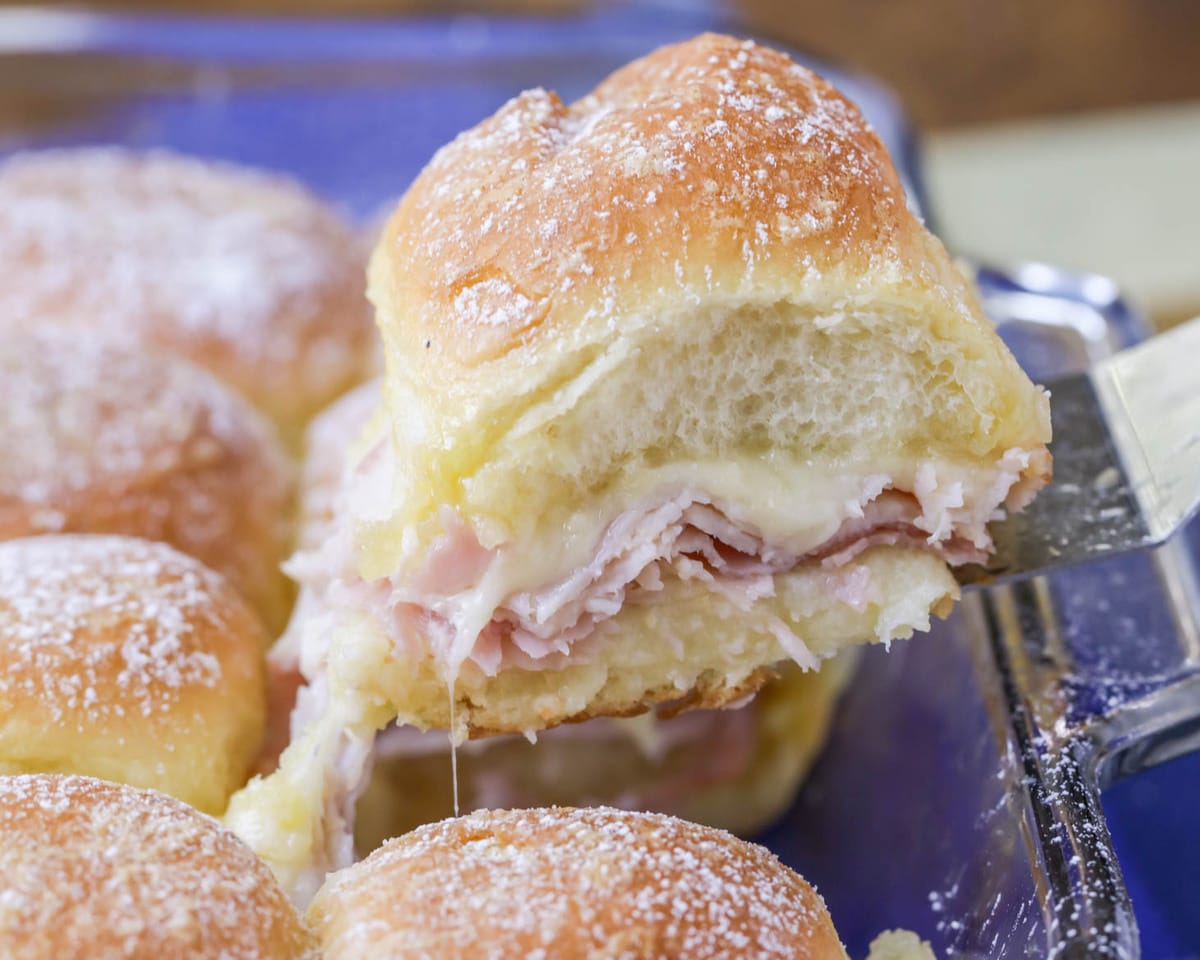 Finger food appetizers - scooping monte cristo sliders from the baking dish.