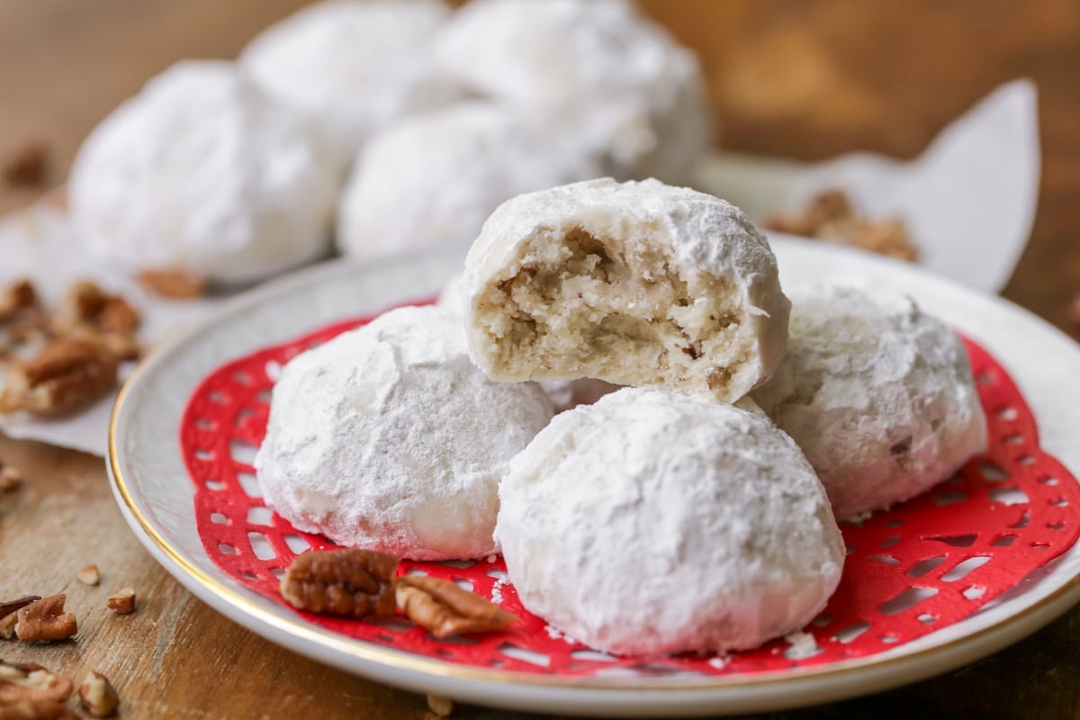 Easy cookie recipes - snowball cookies on a white plate with a bite missing.