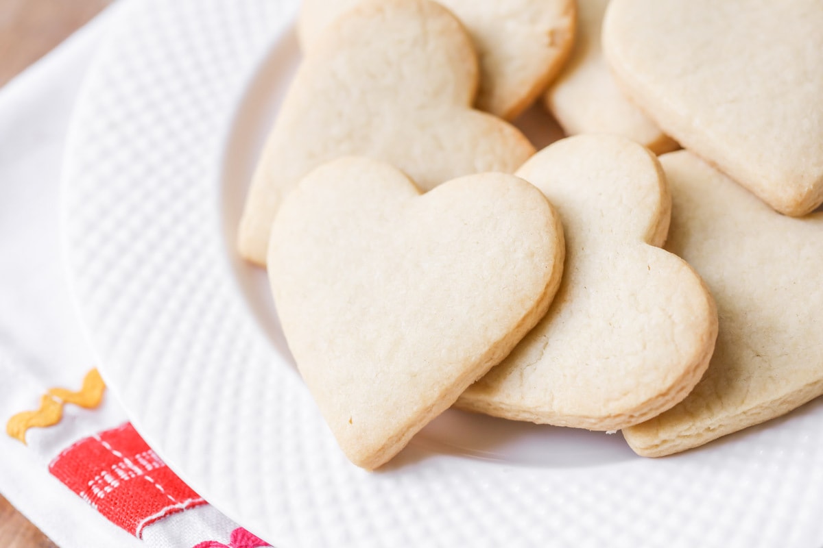 Butter Cookies cut into hearts and stacked on a white plate