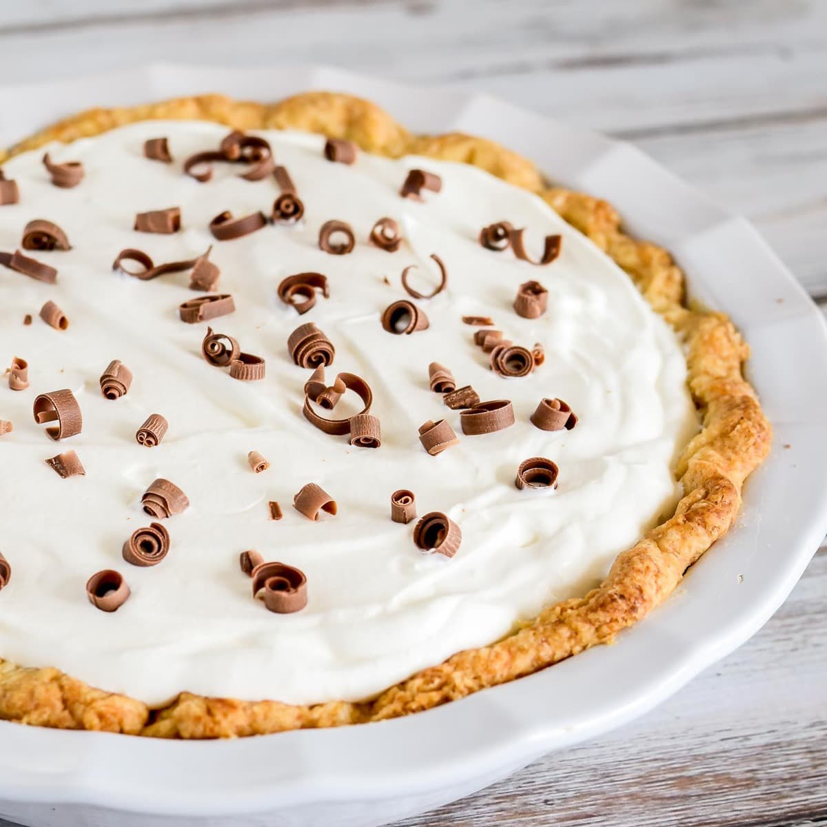 Chocolate Cream Pie topped with whipped cream and chocolate curls in a white pie dish