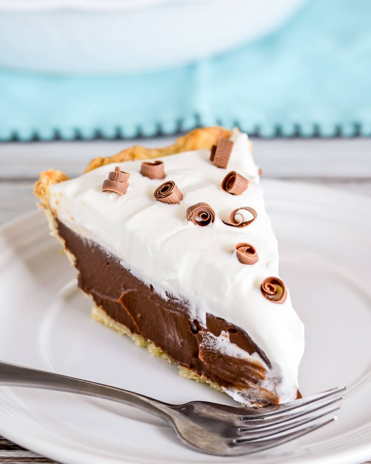 Chocolate Cream Pie recipe slice topped with chocolate curls on a white plate