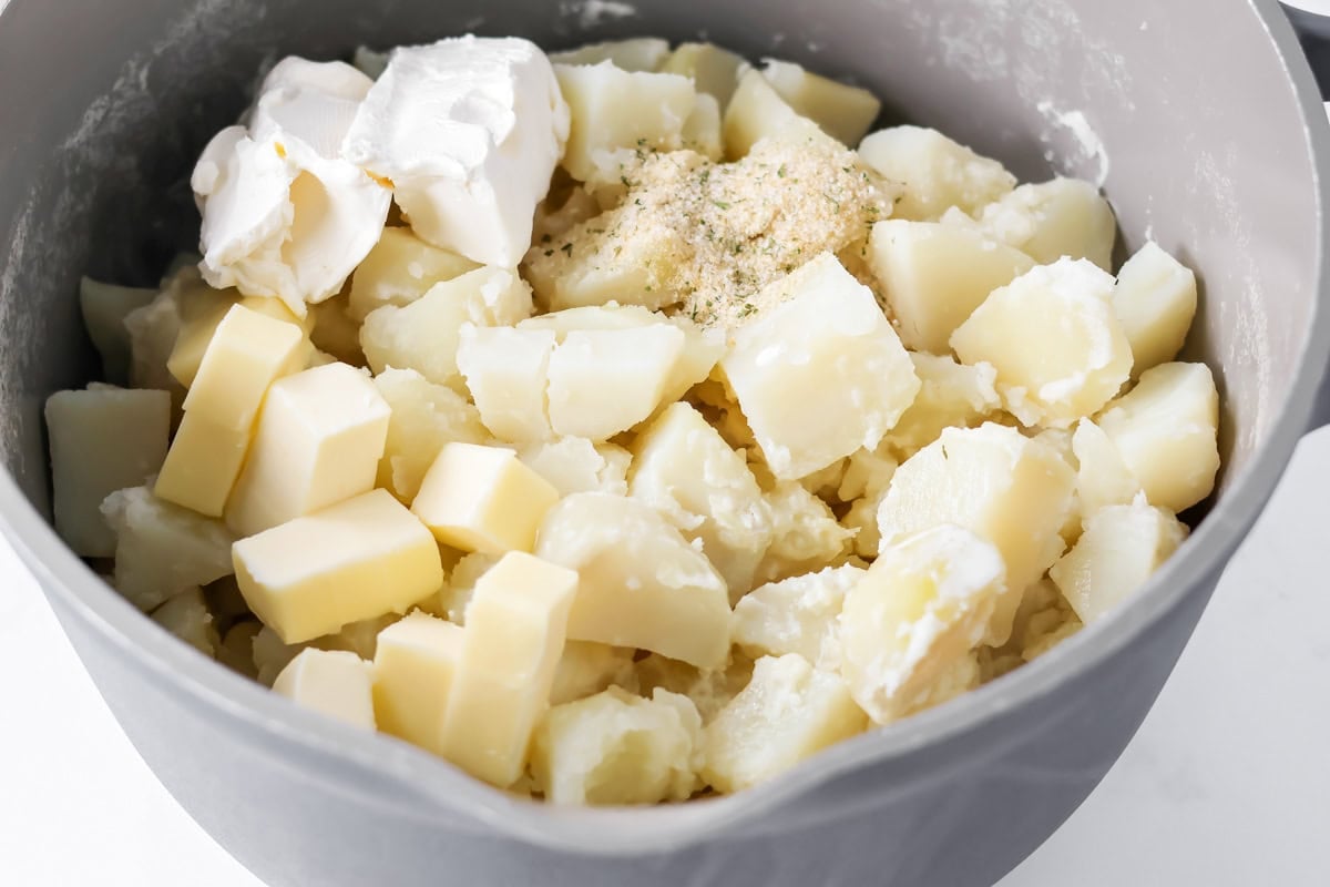 Cooked potatoes with other ingredients in mixing bowl.