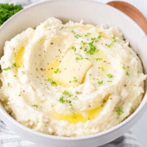 Best mashed potatoes recipe dished into bowl with butter and chives on top.