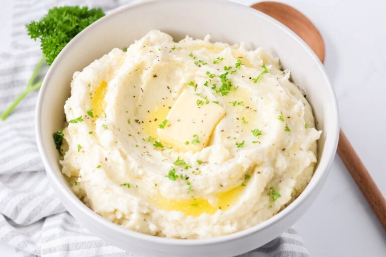 Best mashed potatoes recipe dished into bowl with butter and chives on top.