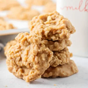 Peanut butter no bake cookies stacked on top of each other near milk bottle.