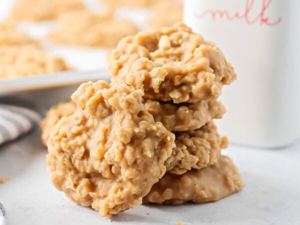 Peanut butter no bake cookies stacked on top of each other near milk bottle.