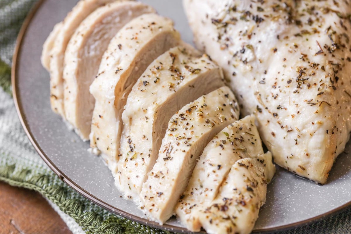 Cooked and sliced chicken on a grey plate.