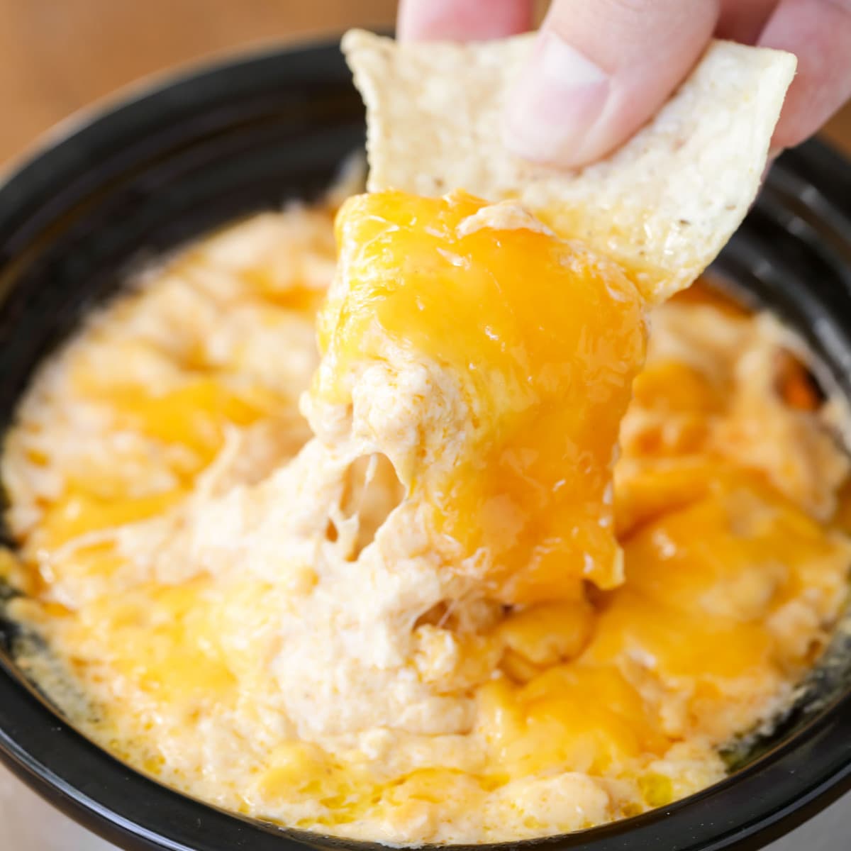 Easy Appetizers - Crock Pot Buffalo Dip with a chip dipped in the dip in a black crock. 