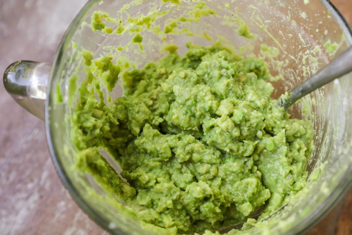 Mashed avocados for homemade guacamole in a glass bowl.