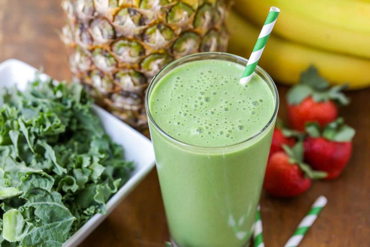 Kale smoothie in a glass with a straw.