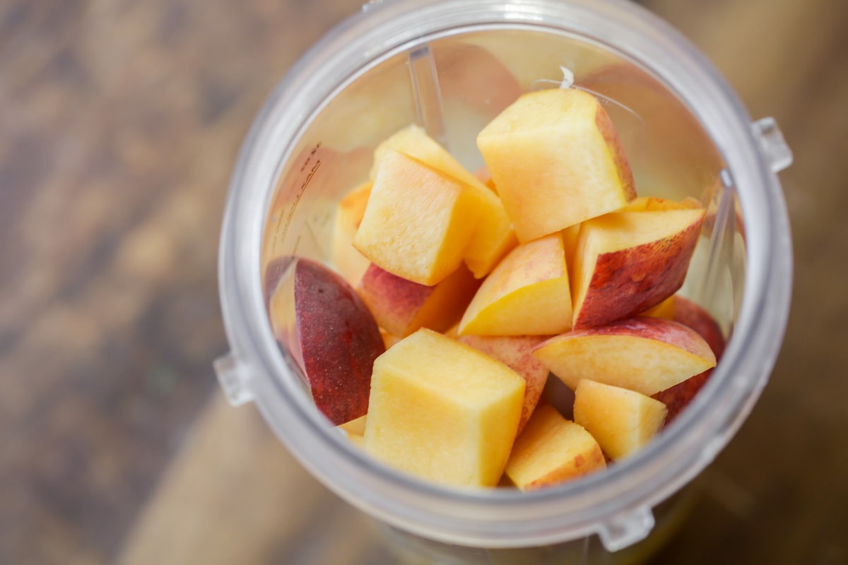 Diced peaches in a blender for a peach smoothie.