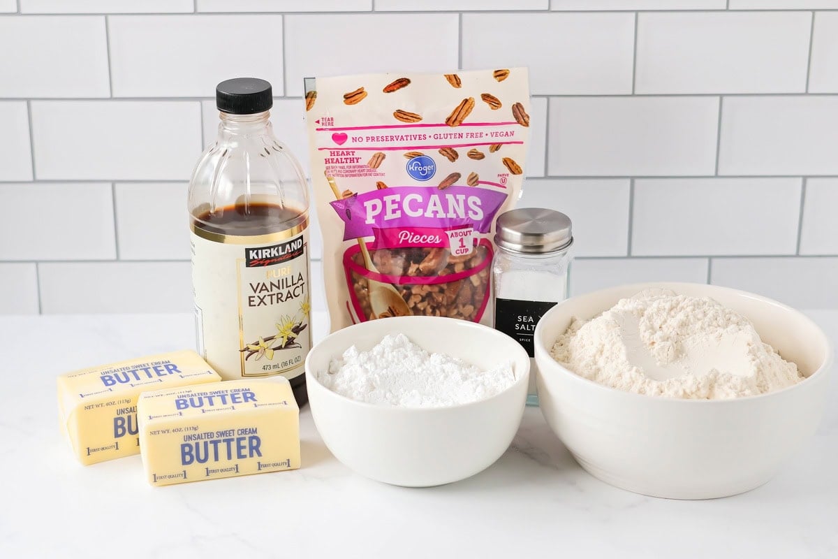 The BEST holiday cookie is our favorite 6-ingredient snowball cookie recipe - loaded with pecans, it's melt-in-your-mouth perfection! Snowball cookies ingredients on white countertop.