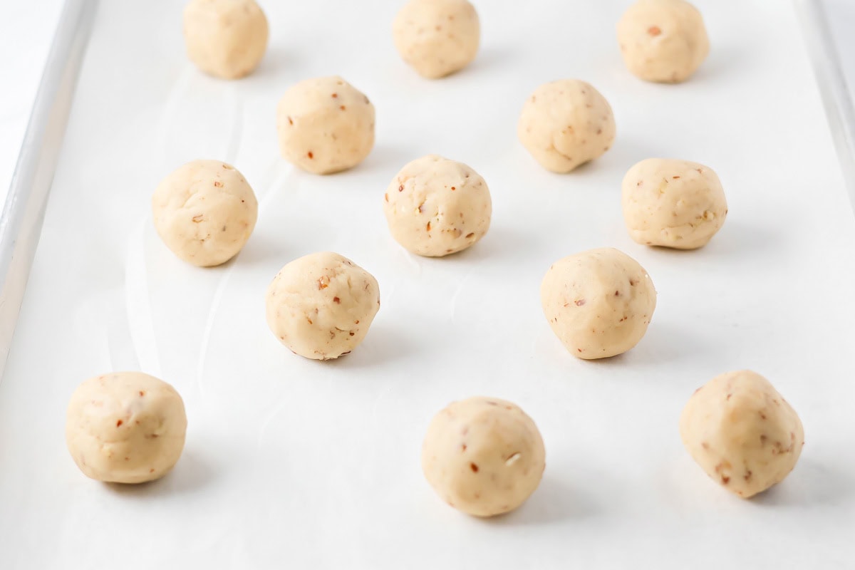 Snowball cookie dough balls on cookie sheet.
