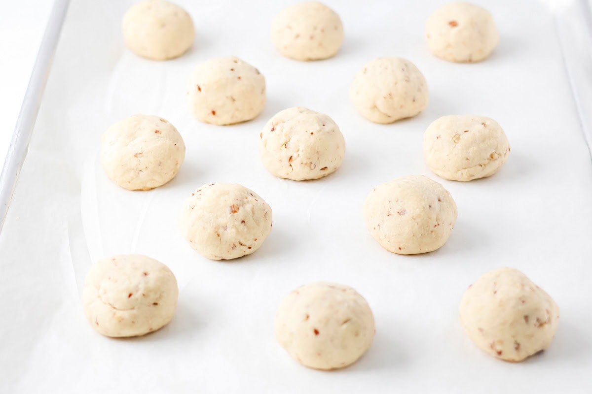 Baked snowball cookies on parchment paper lined baking sheet.
