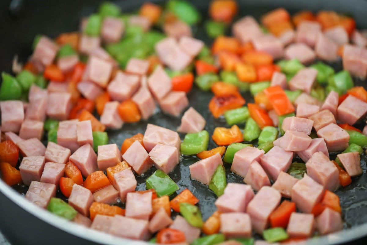 Ham and peppers cooking in a pan.