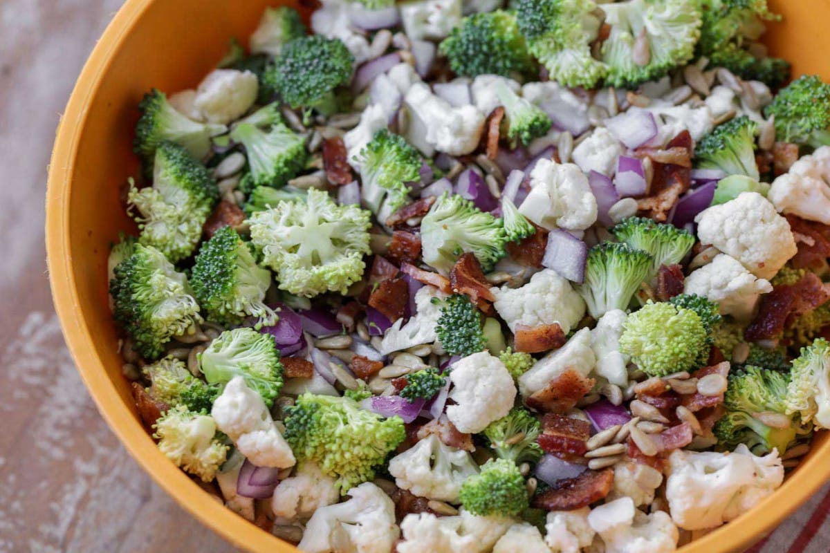 Chopped broccoli, cauliflower, bacon, and onions for making Broccoli Cauliflower Salad.