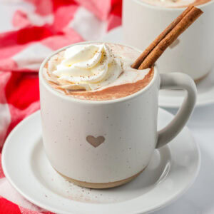 Mexican hot chocolate recipe in cup with cinnamon stick and whipped cream.