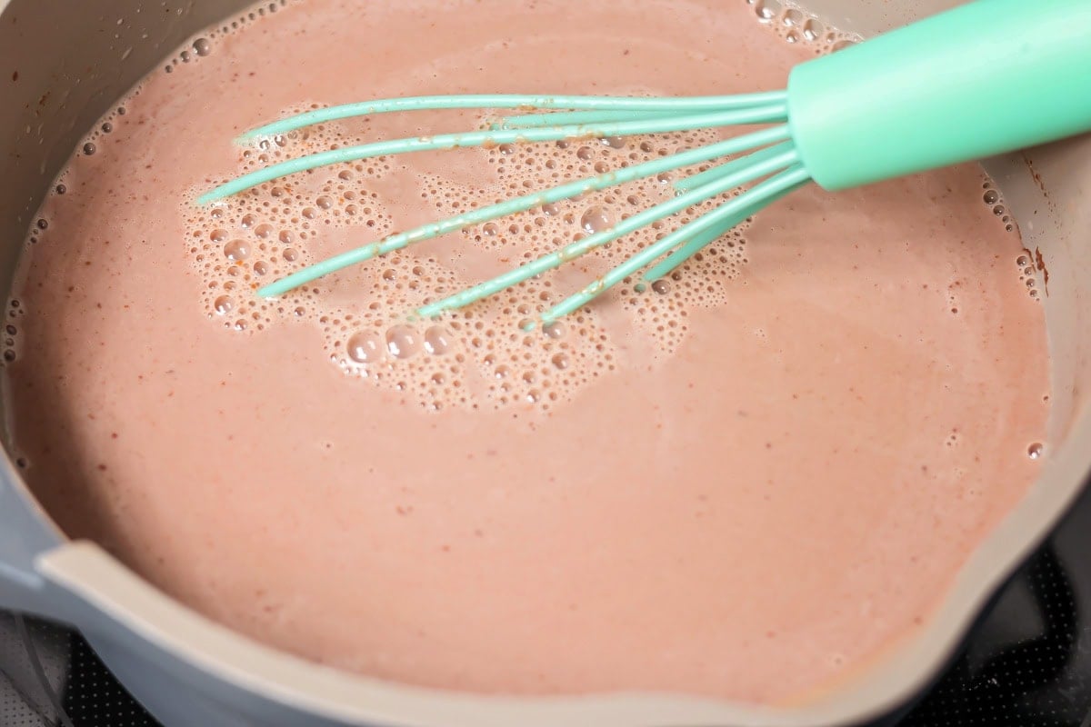 Mexican hot chocolate drink in pot with whisk in it.