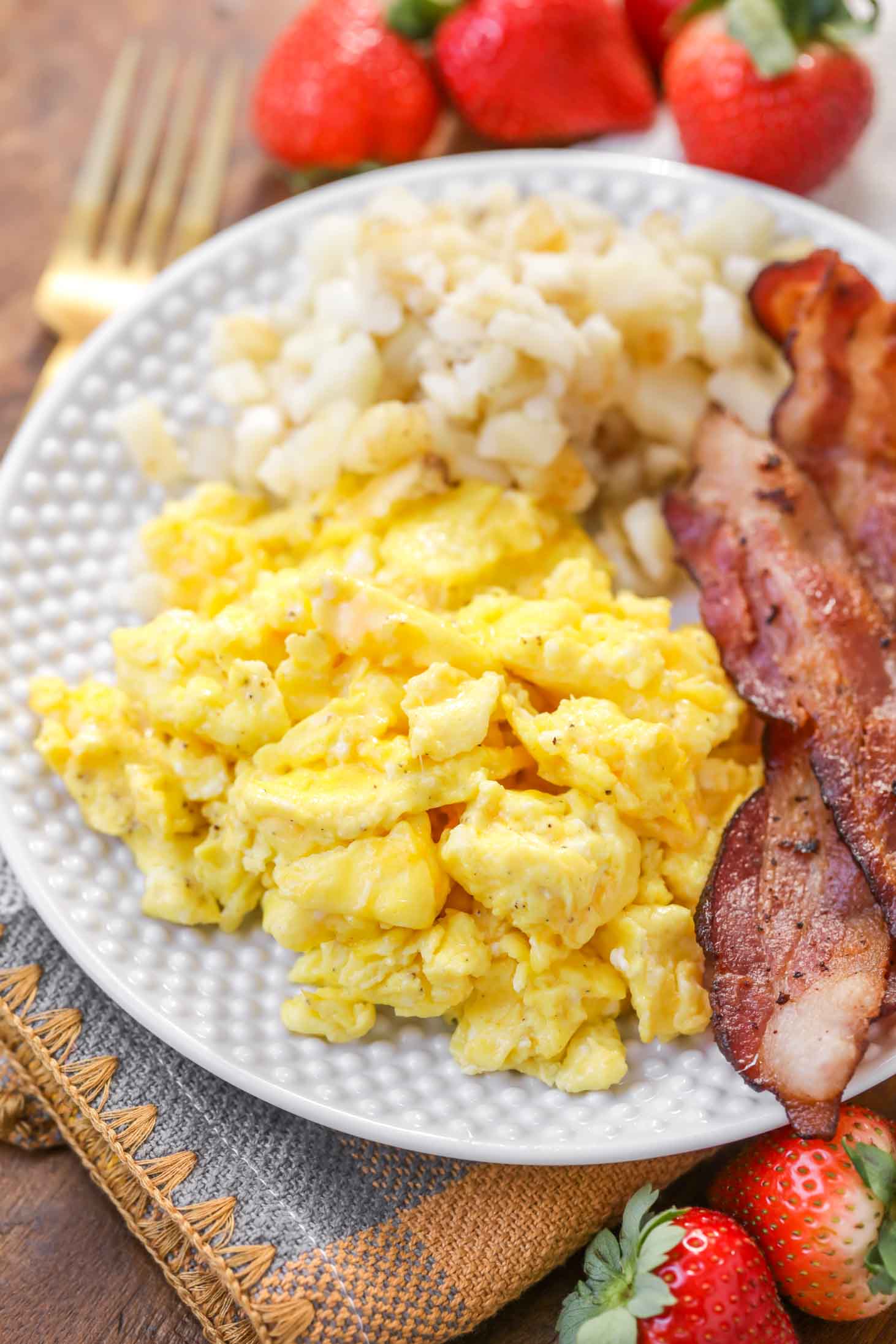 Best Scrambled Eggs recipe on plate with bacon and potatoes.
