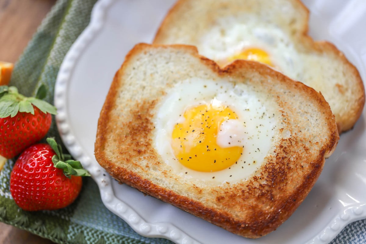 Easy Breakfast Ideas - toasted bread with egg cooked into the middle on a white plate. 