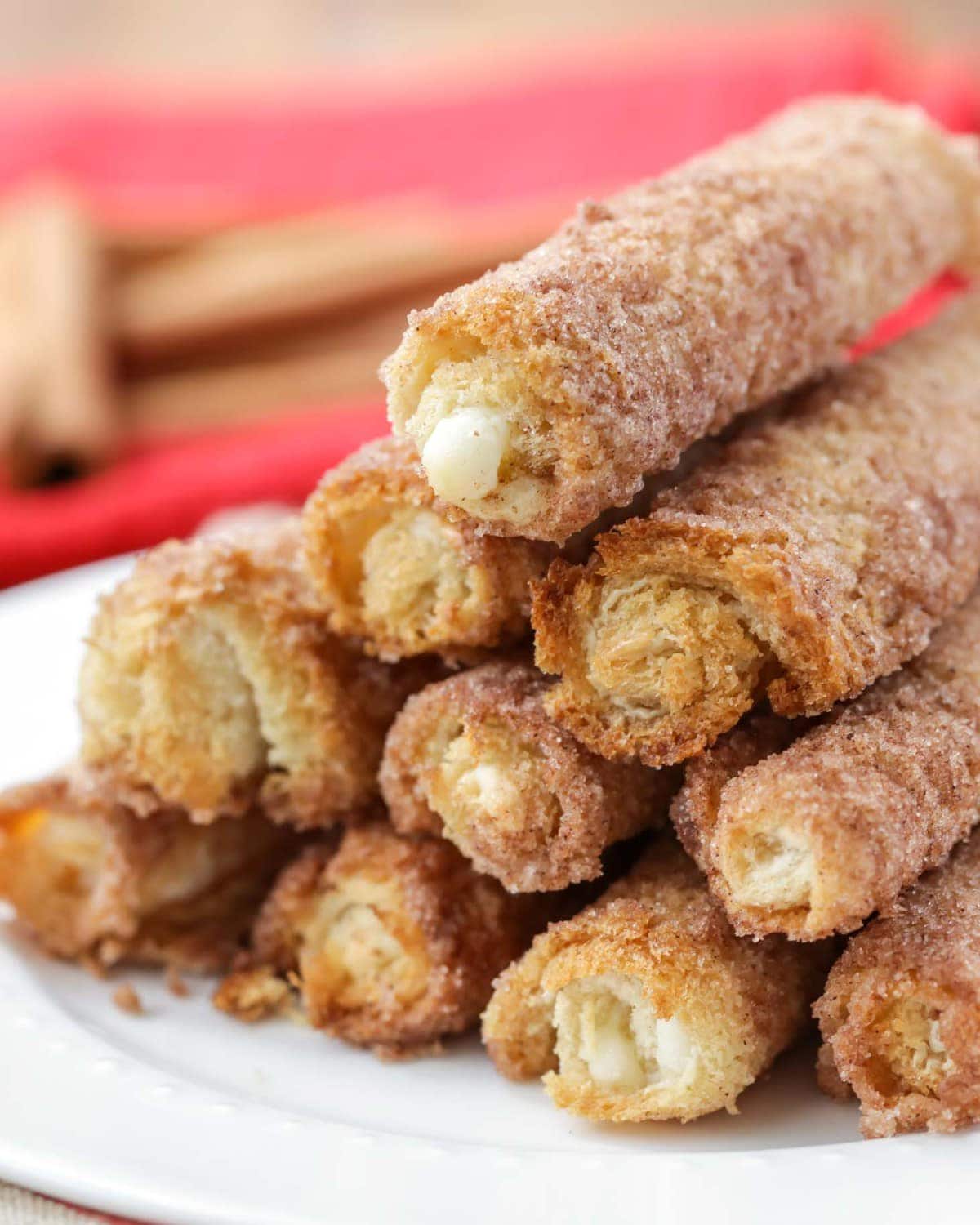 Cinnamon cream cheese roll ups stacked on a white plate