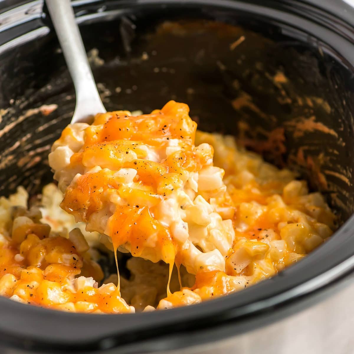 Crockpot Cheesy Potatoes scooped from a slow cooker.
