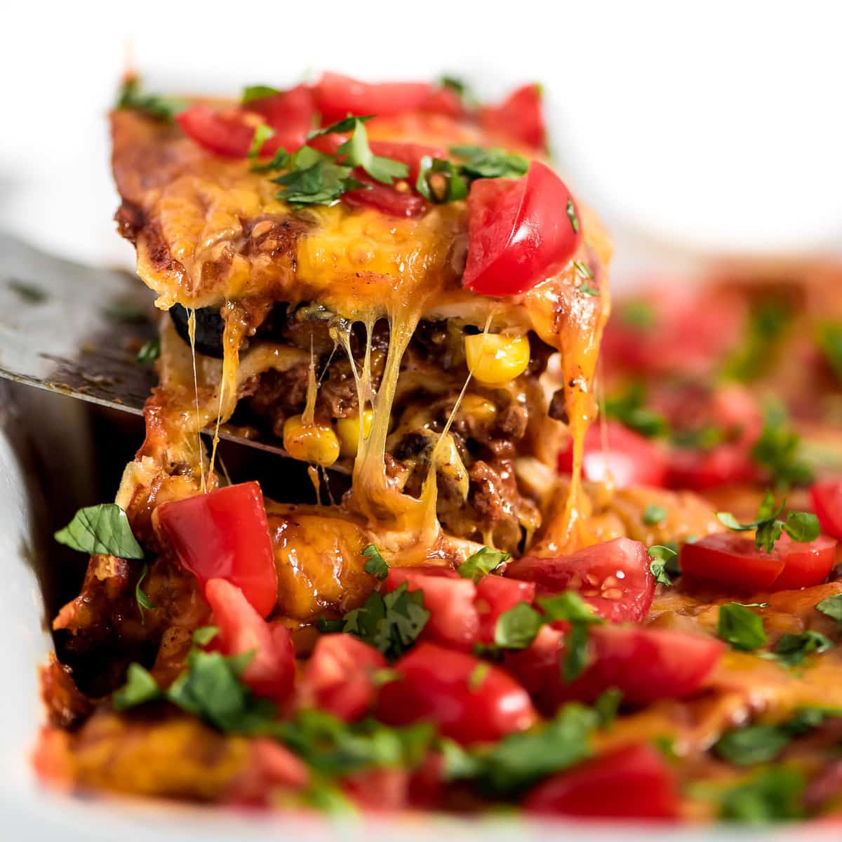 Easy Dinner Ideas - Enchilada casserole being served on a metal spatula.