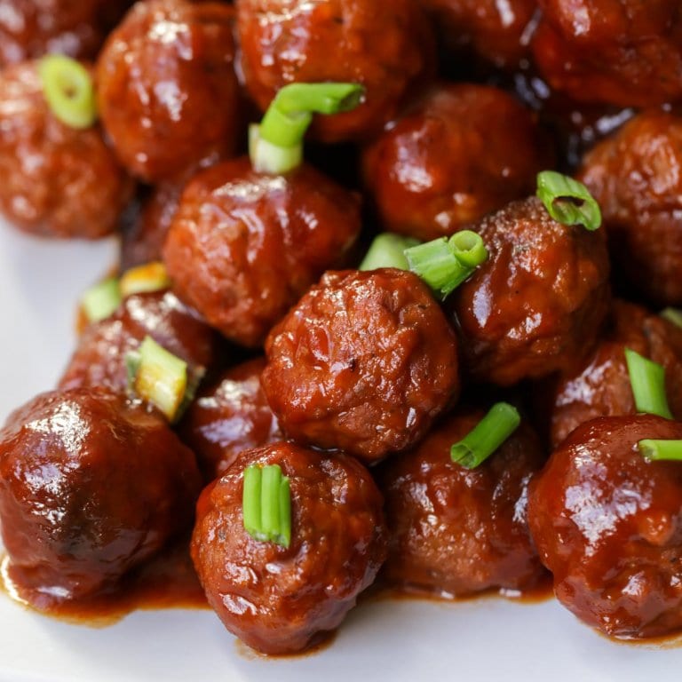 Grape Jelly Meatballs close up image with green onions on top.