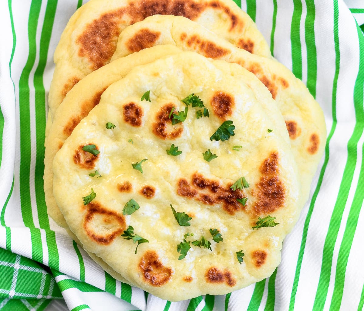 Yeast bread recipes - close up of homemade naan bread topped with fresh herbs.