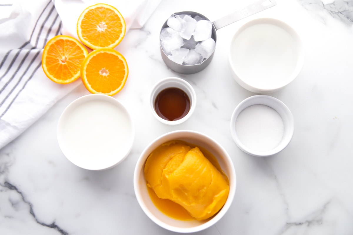 Orange Julius ingredients on a marble countertop.