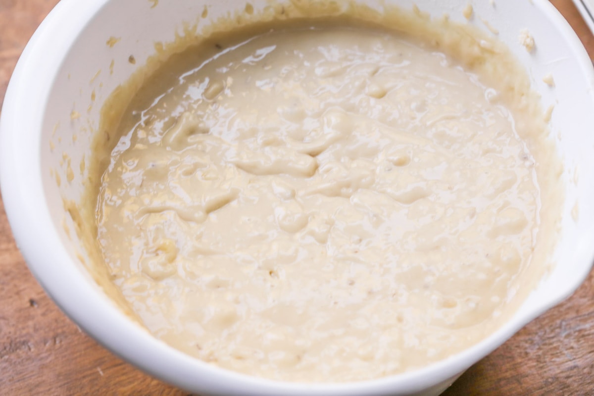 Banana batter in a white bowl.